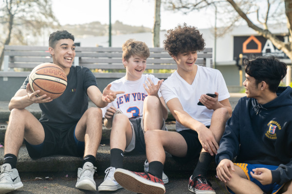 Children sitting next to basketball court