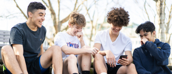 A group of teenage males sitting together and looking at a phone