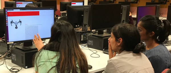 Three women working together on a computer to solve a problem