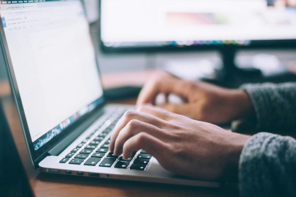 Pairs of hands typing on laptop keyboard