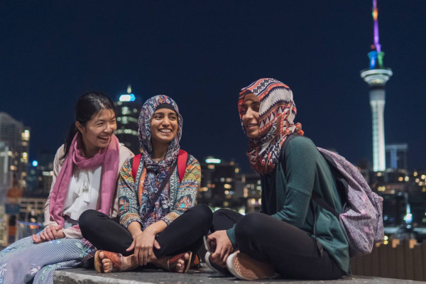 Three women sitting with city lights in the background