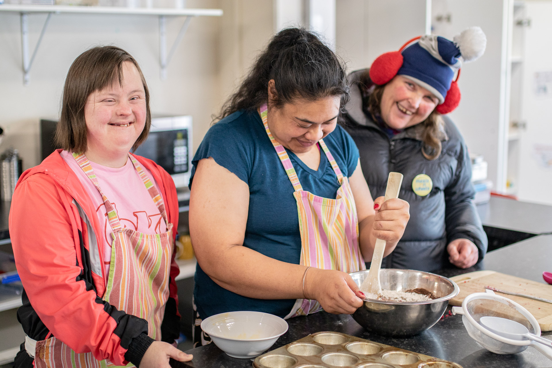 Three people smiling while baking