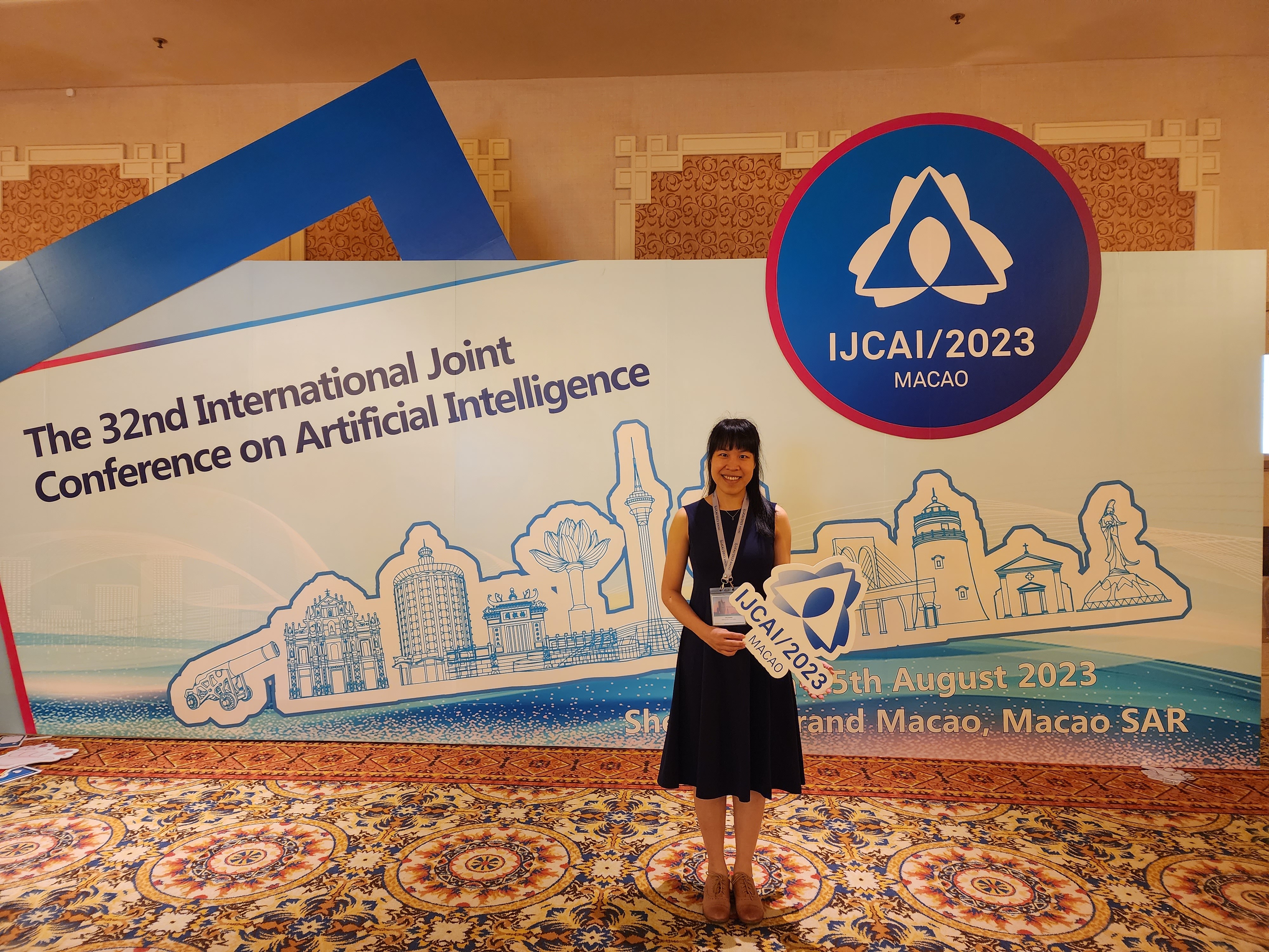A woman posing in front of a conference billboard for Conference on AI