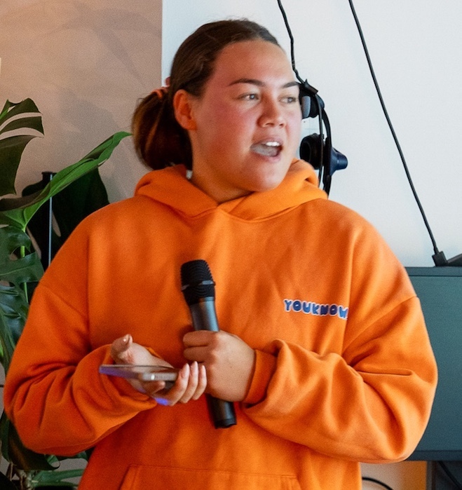 Teenager speaking into a microphone and looking at the audience.