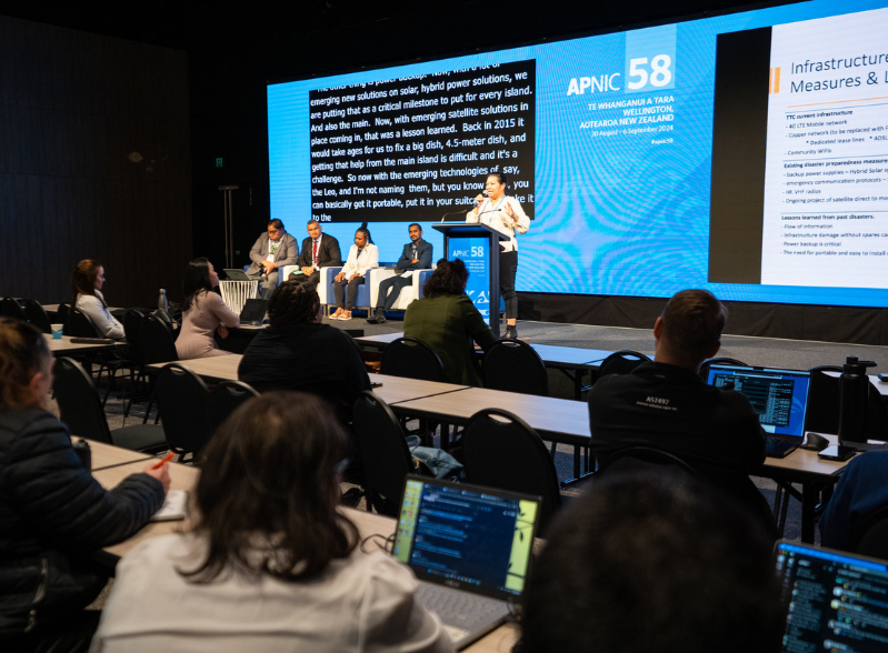 A group of people watching a conference panel take place